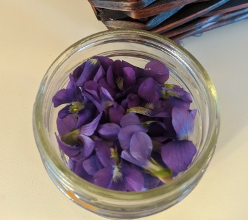 A glass jar filled with violet flowers.